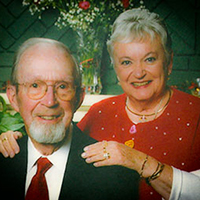 man sitting and woman with hand on man's shoulders